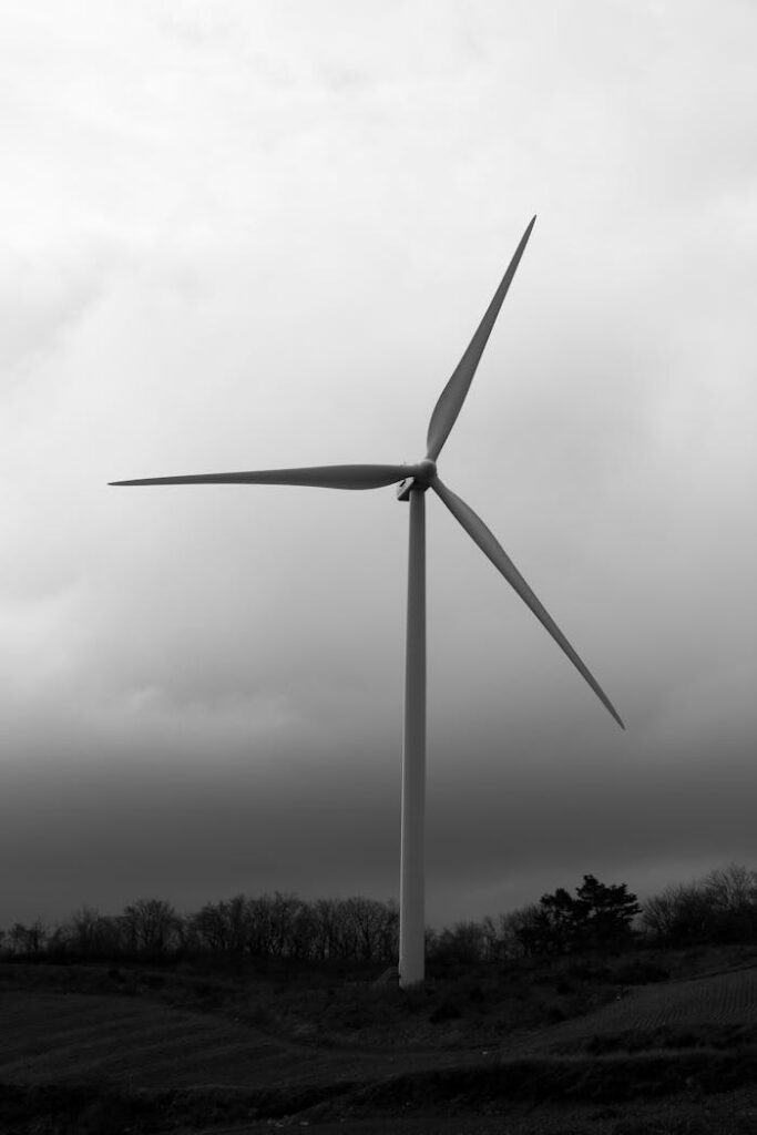 A towering wind turbine against a dramatic cloudy sky in the countryside.